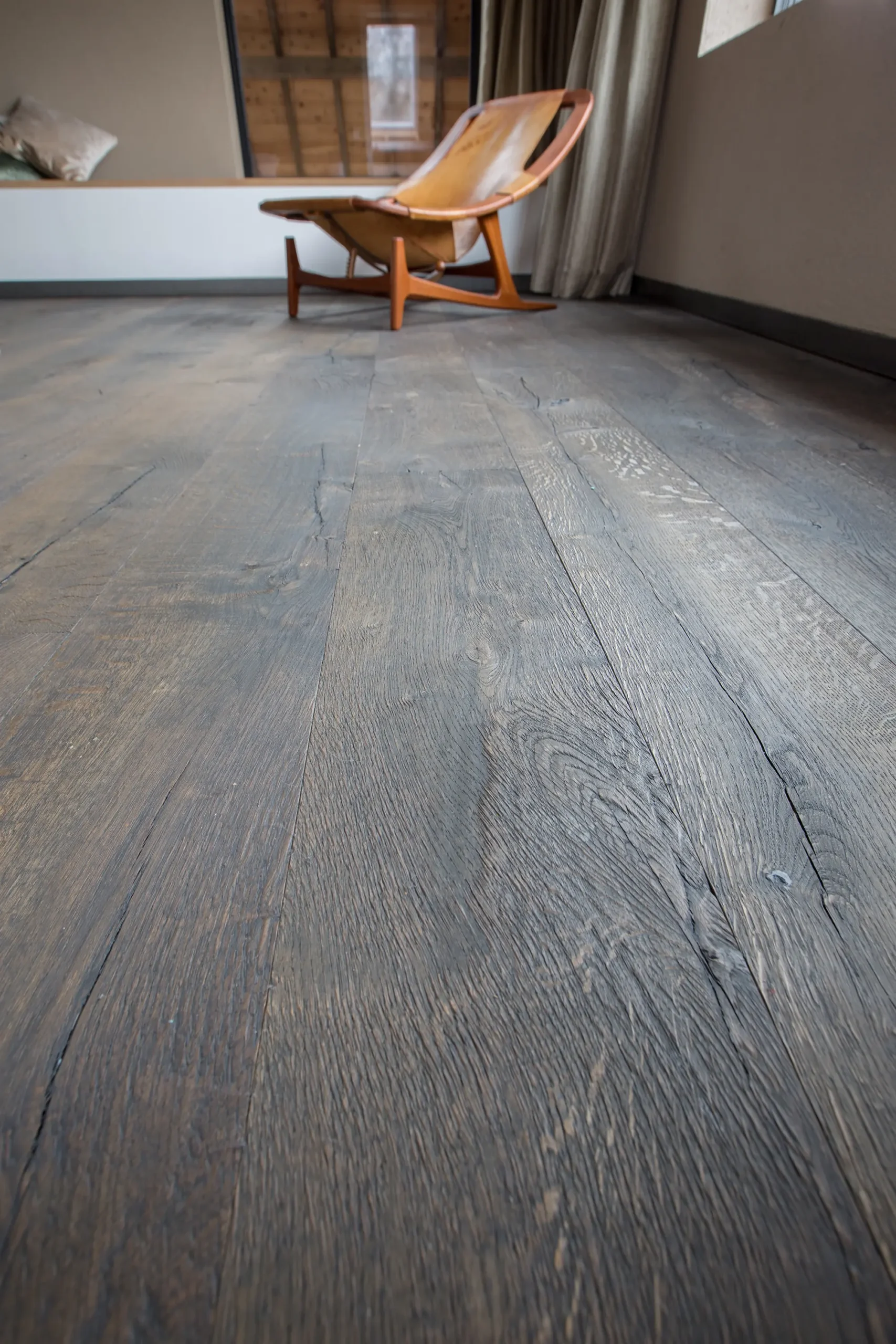 Houten vloer collectie Raftwood kleur donkerbruin in een slaapkamer met een stoel van visser parket te rijssen